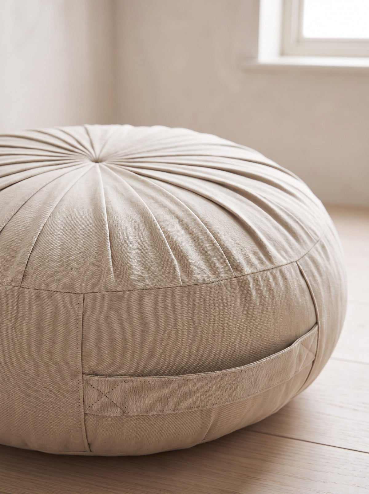 Close-up of the pleated cotton cover and fabric handle of the meditation cushion