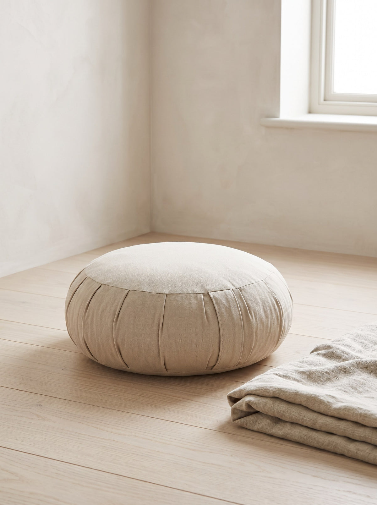 Oat Buckwheat Meditation Cushion on an oak floor beside a folded linen throw