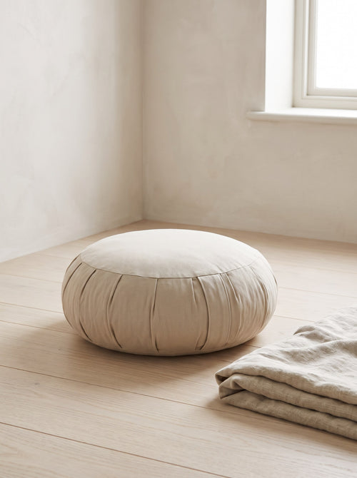 Oat Buckwheat Meditation Cushion on an oak floor beside a folded linen throw