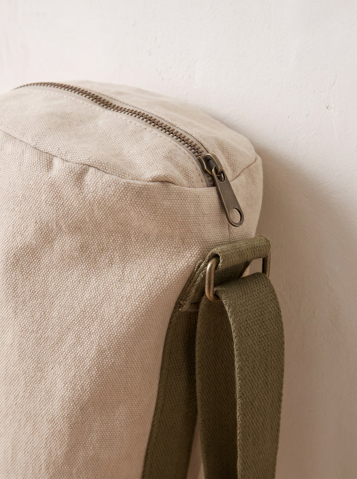Close-up of the zip, canvas weave and olive cotton strap of the yoga mat bag