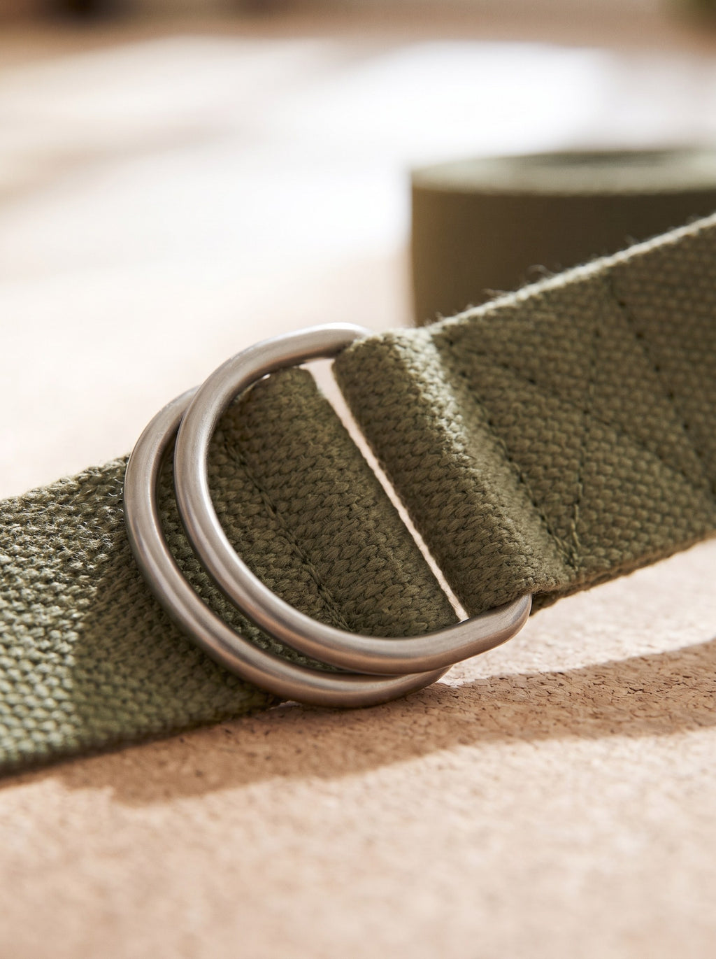 Close-up of the woven cotton and brushed metal D-ring buckle of the yoga strap