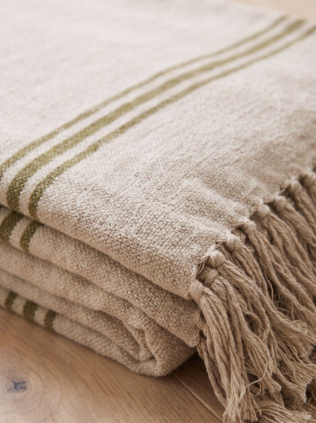 Close-up of the woven cotton texture, olive stripe and fringe of the yoga blanket