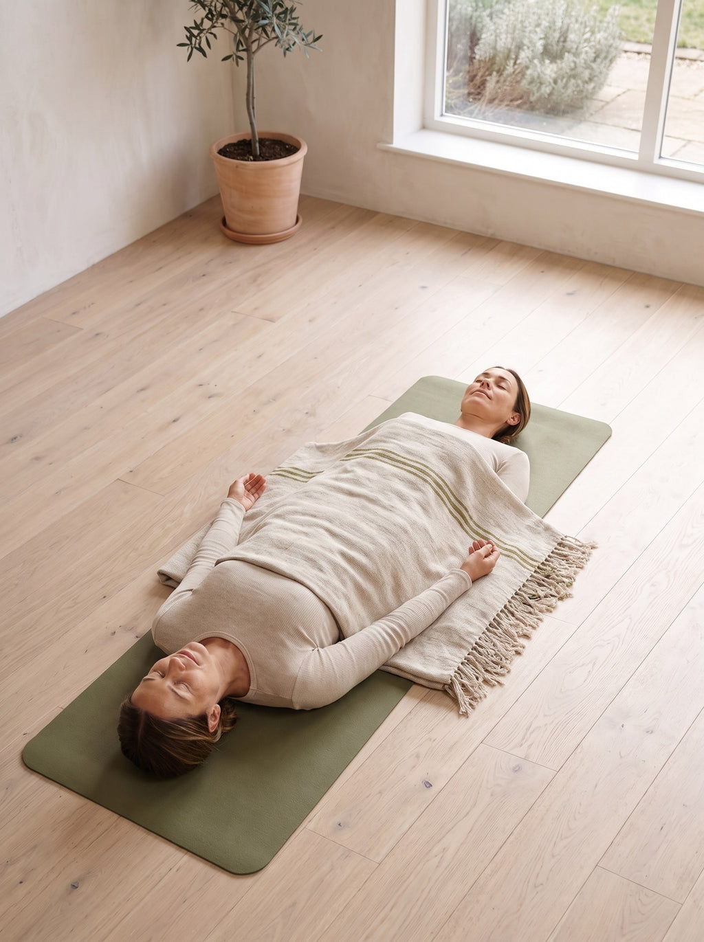 Woman resting in savasana covered with the Woven Cotton Yoga Blanket